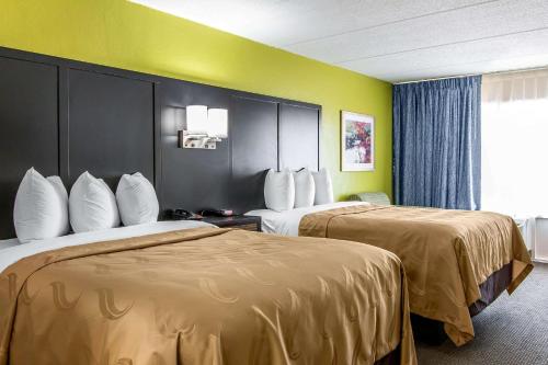 海恩斯維爾的住宿－Quality Inn Hinesville - Fort Stewart Area, Kitchenette Rooms - Pool - Guest Laundry，两张床位于带黄色墙壁的酒店客房