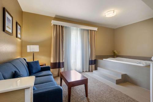 sala de estar con sofá azul y bañera en Comfort Inn & Suites Pittsburg, en Pittsburg