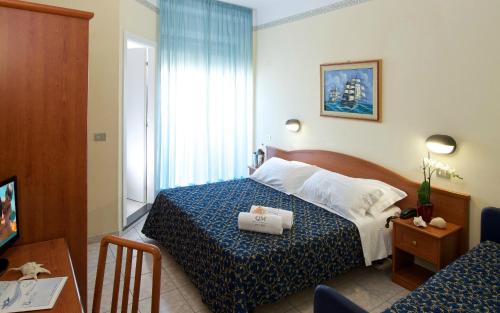 a hotel room with a bed with a blue and white bedspread at Hotel Queen Mary in Cattolica