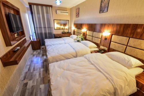 a hotel room with three beds and a flat screen tv at MARİNA HOTEL in Izmir