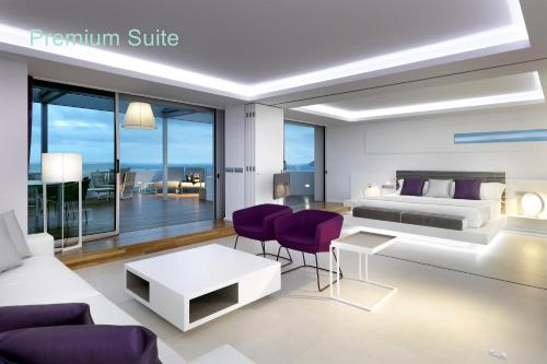 a bedroom with a king bed and purple chairs at Hotel Garbi Ibiza & Spa in Playa d'en Bossa