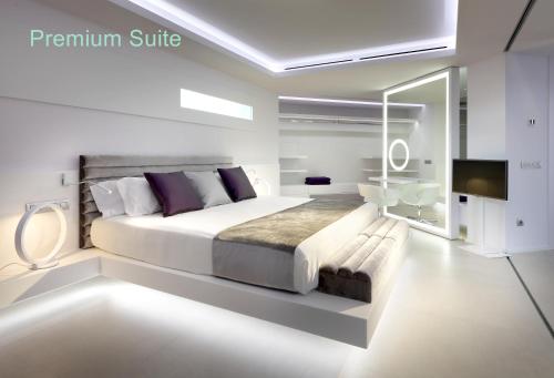 a white bedroom with a large bed and a tv at Hotel Garbi Ibiza & Spa in Playa d'en Bossa