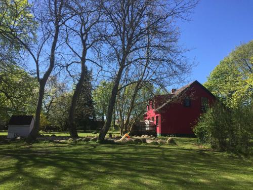 um celeiro vermelho no meio de um campo com árvores em Ferienhaus 1 _ Ferien im Gutspark em Mattchow