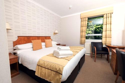 a hotel room with a bed and a desk and a window at Pitbauchlie House Hotel - Sure Hotel Collection by Best Western in Dunfermline
