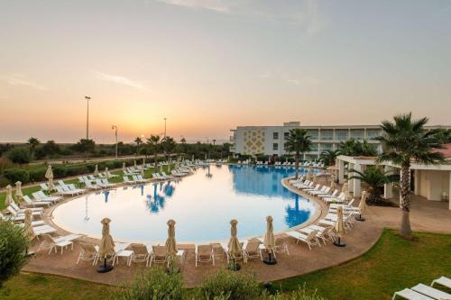 a large pool with white chairs and a resort at Radisson Blu Resort Saidia Beach in Saidia 