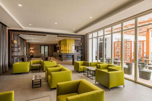 a lobby with yellow chairs and tables and windows at Radisson Blu Resort Saidia Beach in Saidia 