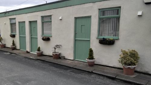 a building with green doors and potted plants on a street at The Old Colliery Stables in Durham
