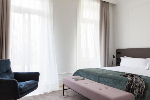 a bedroom with a bed and a couch and a chair at Kozmo Hotel Suites & Spa - Small Luxury Hotels of the World in Budapest
