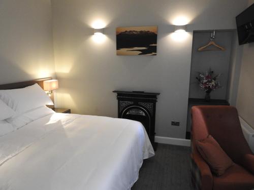 a bedroom with a bed and a chair and a fireplace at House of Juniper in Broadford