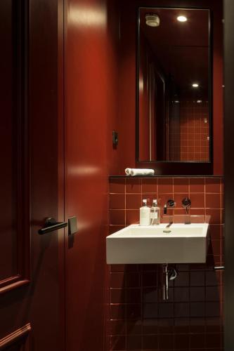 a bathroom with a white sink and a mirror at Kozmo Hotel Suites & Spa - Small Luxury Hotels of the World in Budapest