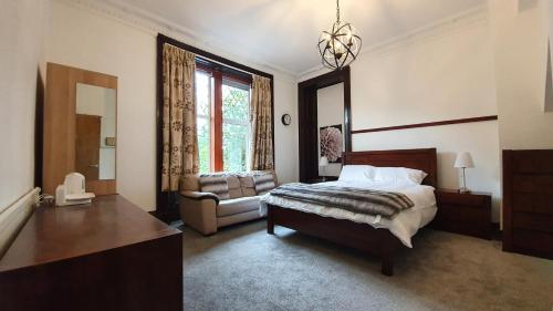 a bedroom with a bed and a chair and a window at Bemersyde Villa-Studios in Mansewood