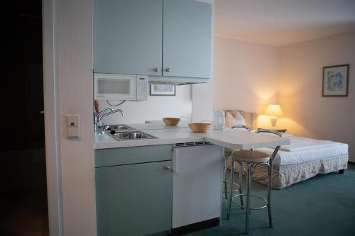a kitchen with a sink and a table with a bed at pepb Schulungshotel in Sarstedt