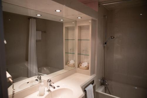 a bathroom with a sink and a shower and a mirror at pepb Schulungshotel in Sarstedt