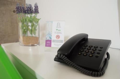 un teléfono negro sentado en una mesa junto a un jarrón de flores en Torre Potosi Departamentos en Rosario