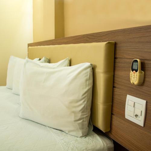 a bed with a white pillow and a phone on a headboard at Larison Executive by Easy Hotéis in Porto Velho