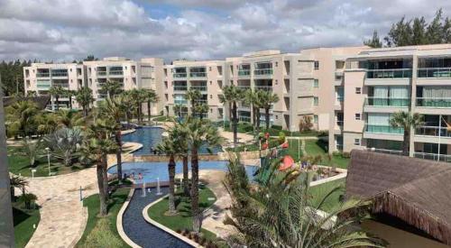 a large apartment building with a pool and palm trees at Aquiraz Riviera in Aquiraz