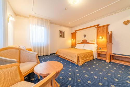 a hotel room with a bed and a chair at Pineta Pastry Hotel in Rocca Pietore