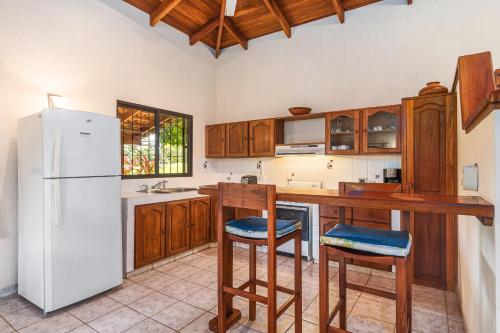 a kitchen with a white refrigerator and wooden cabinets at Guacamaya Lodge in Paraíso