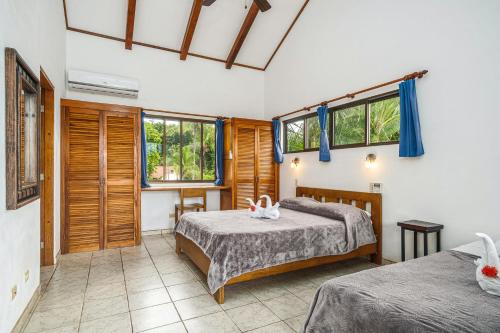 a bedroom with two beds and two windows at Guacamaya Lodge in Paraíso
