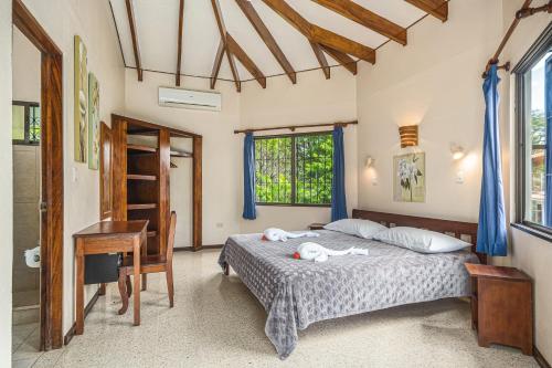 a bedroom with a bed and a desk and windows at Guacamaya Lodge in Paraíso