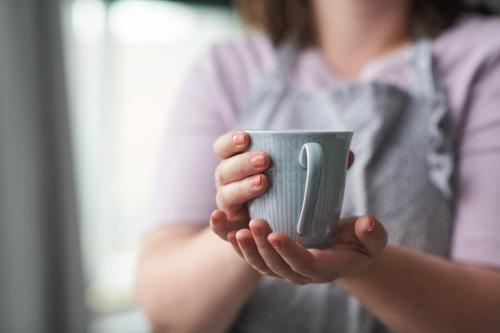 una mujer sosteniendo una taza en sus manos en Hotell Rådhuset en Lidköping