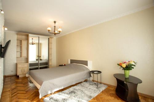1 dormitorio con 1 cama y un jarrón de flores sobre una mesa en Уютная квартира в центре, en Mykolaiv