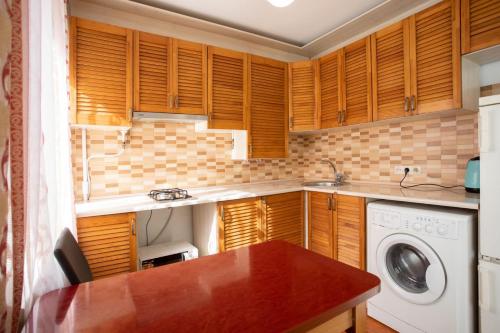 a kitchen with wooden cabinets and a washing machine at Уютная квартира в центре in Mykolaiv