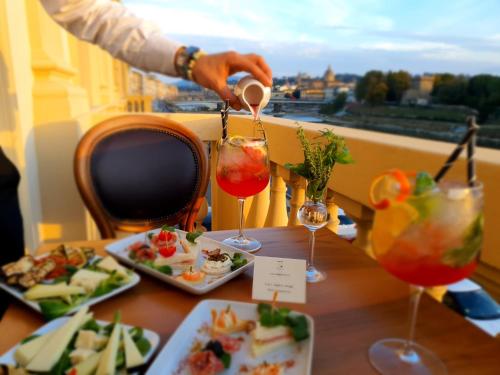 a person pours a drink in glasses on a table with food at Hotel Lungarno Vespucci 50 in Florence