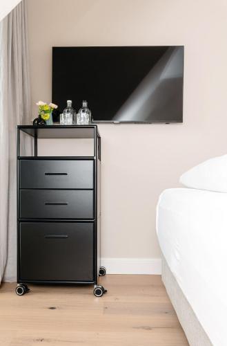 a black dresser with a tv on a wall in a bedroom at Jaumann's Südwind Sylt in Westerland (Sylt)