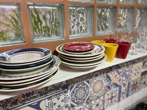 a bunch of plates and cups on a shelf at Casa Solana - confortável, em rua calma, no centro do Rosa in Imbituba