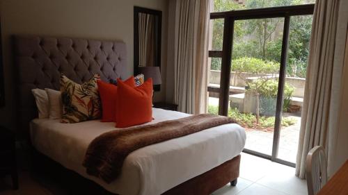 a bedroom with a bed with orange pillows and a window at Zimbali Suites 223 in Ballito