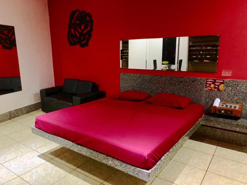 um quarto vermelho com uma cama grande e uma cadeira preta em Motel Emoções (Adults Only) em Fortaleza