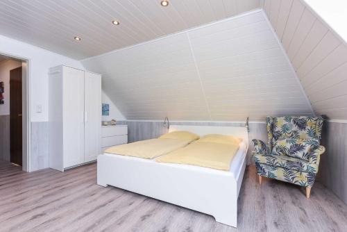 a bedroom with a white bed and a chair at Haus Windliese Apartments in Bensersiel