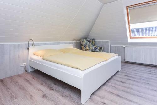ein weißes Bett in einem Zimmer mit Fenster in der Unterkunft Haus Windliese Apartments in Bensersiel