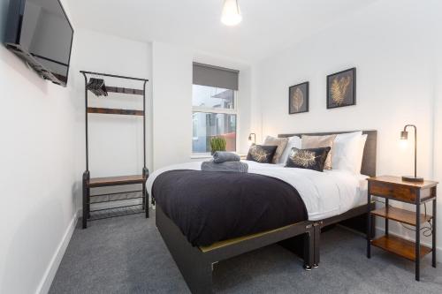 een slaapkamer met een groot bed en een televisie bij Charles Alexander Short Stay - Charnley House Apartments in Blackpool
