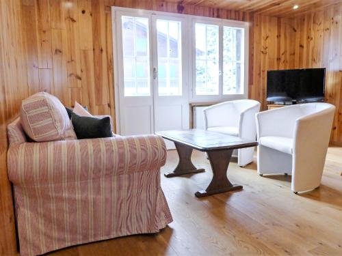 ein Wohnzimmer mit einem Sofa, einem Tisch und Stühlen in der Unterkunft Apartment Chalet Anna by Interhome in Grindelwald