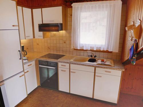 a small kitchen with white cabinets and a sink at Apartment Wiedersehn Dachgeschoss by Interhome in Grächen
