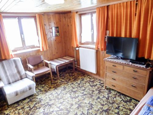 um quarto com uma televisão, uma cadeira e uma cómoda em Apartment Heiderösli-1 by Interhome em Grächen
