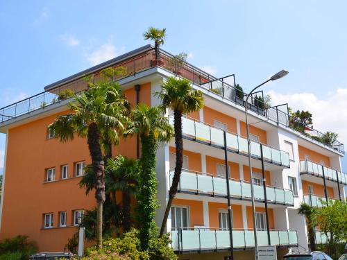 ein orangefarbenes Gebäude mit Palmen davor in der Unterkunft Apartment Corallo - Utoring-22 by Interhome in Ascona