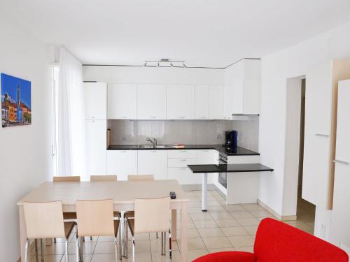 eine weiße Küche mit einem Tisch und Stühlen in der Unterkunft Apartment Corallo - Utoring-22 by Interhome in Ascona