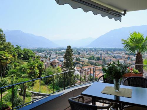 einen Balkon mit einem Tisch, Stühlen und Bergen in der Unterkunft Apartment Suite Modern-18 by Interhome in Ascona