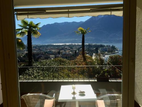 Blick auf einen Tisch und Palmen aus dem Fenster in der Unterkunft Apartment Double Room Classic-8 by Interhome in Ascona