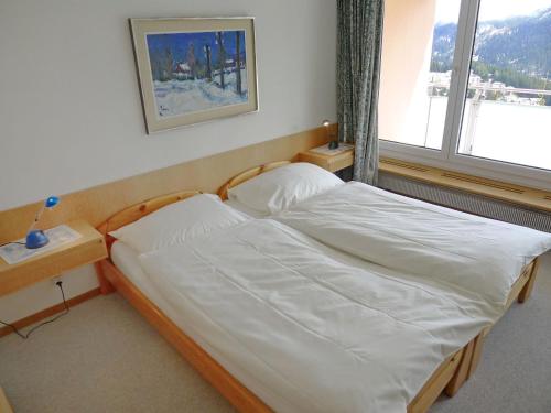 Schlafzimmer mit einem Bett mit weißer Bettwäsche und einem Fenster in der Unterkunft Apartment Promenade - Utoring-76 by Interhome in Arosa