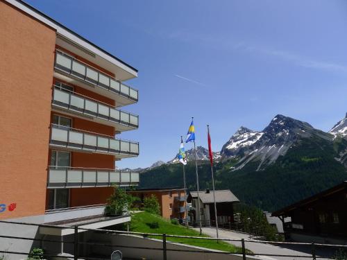 ein Gebäude vor einem Berg mit zwei Flaggen in der Unterkunft Apartment Promenade - Utoring-11 by Interhome in Arosa