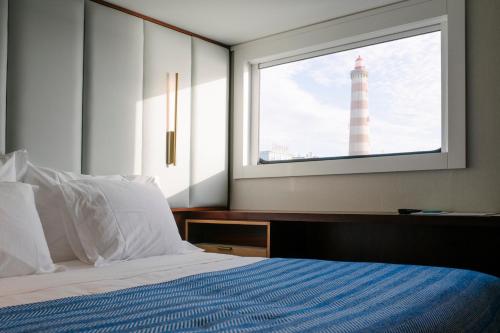 a bedroom with a bed with a lighthouseseen through a window at Costa do Sal Hotel Boat Lounge in Aveiro