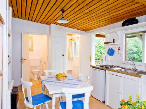 eine Küche mit einem Tisch, Stühlen und einem Waschbecken in der Unterkunft Holiday Home Geesthof-1 by Interhome in Klint