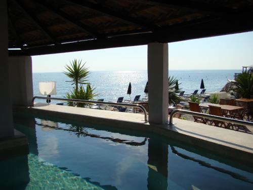 a swimming pool with a view of the ocean at Hôtel Pineto in Biguglia