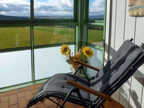een schommelstoel met een vaas met zonnebloemen in een raam bij Apartment G 103 by Interhome in Dittishausen