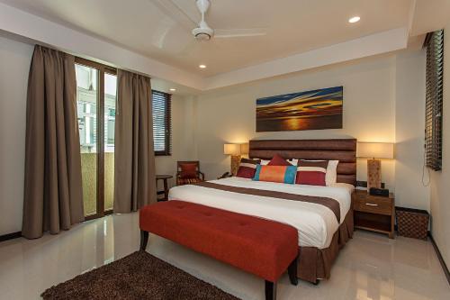 馬累的住宿－薩默塞特酒店，一间卧室设有一张大床和一张红色长凳