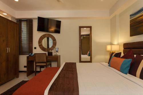 a bedroom with a bed with a desk and a mirror at The Somerset Hotel in Male City
